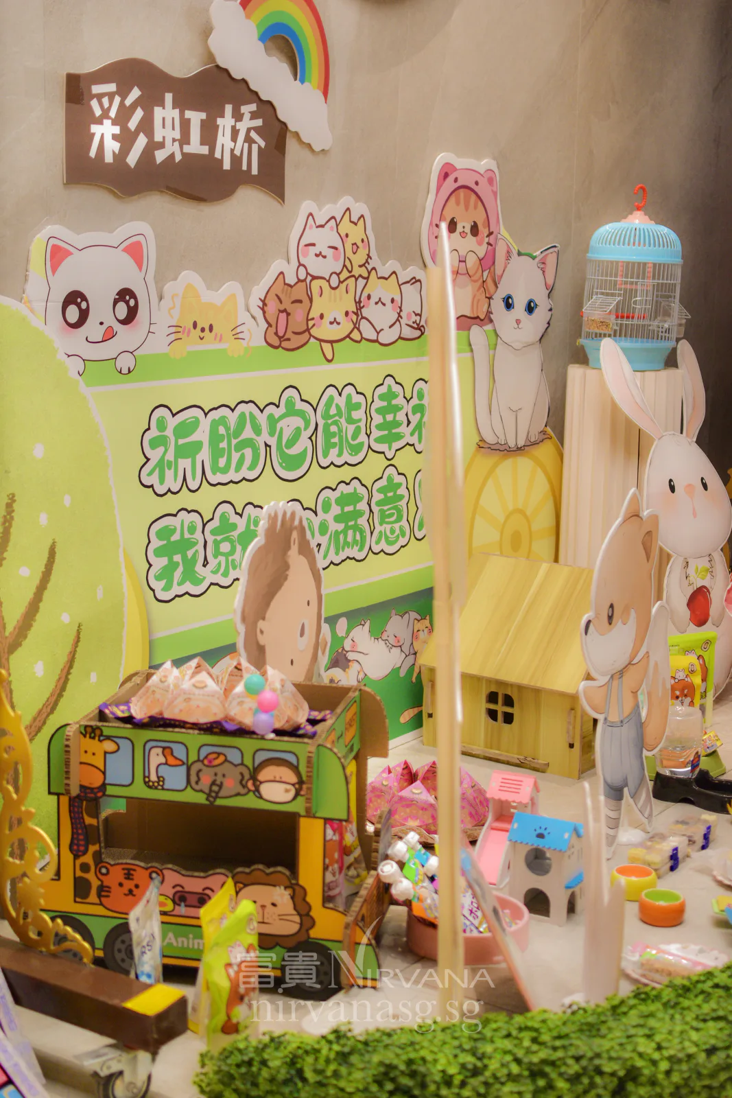 The 彩虹桥 Rainbow Bridge corner at the Seventh Month prayer services at Nirvana, with illustrated cats and rabbits, a paper bus of folded lotuses, a bird cage and a small wooden house