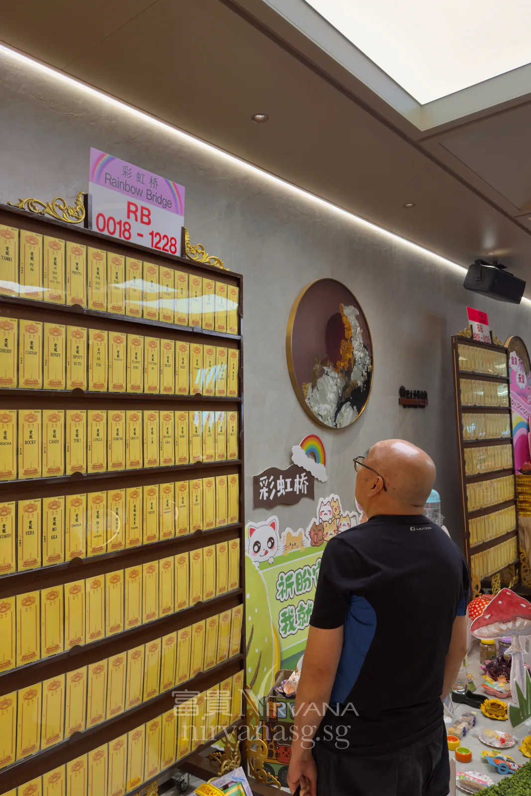 A visitor looks up at the wall of yellow memorial tablets under the 彩虹桥 Rainbow Bridge sign at the Seventh Month prayer services at Nirvana