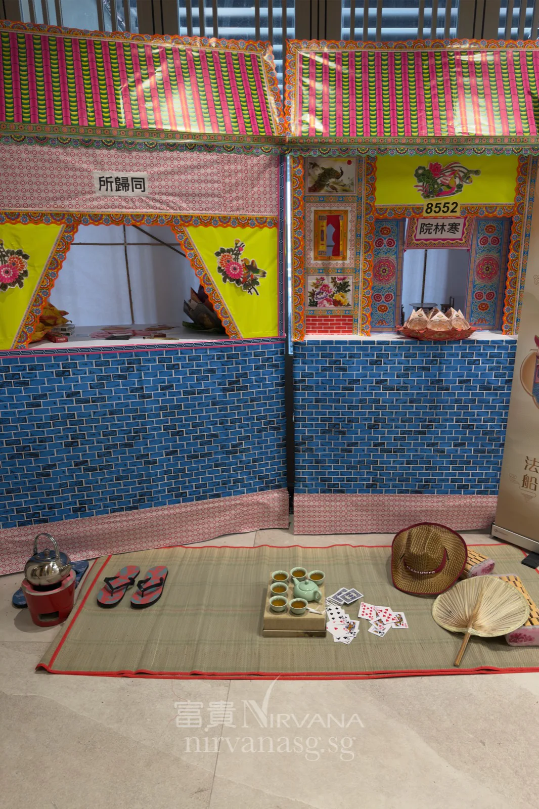 Paper houses labelled 同归所 Tong Gui Suo and 寒林院 Han Lin Yuan at the Seventh Month prayer services, with a straw mat of tea, slippers and everyday offerings laid before them